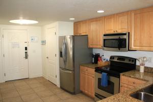 a kitchen with wooden cabinets and a stainless steel refrigerator at Coastal Serenity in St Pete Beach