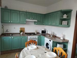 a kitchen with green cabinets and a table with chairs at Casa Pascual in San Mamede de Carnota
