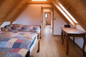 a attic bedroom with two beds and a desk at Vinařská búda nad golfem in Skalica