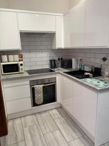 a kitchen with white cabinets and a stove top oven at Grooms cottage in South Collingham