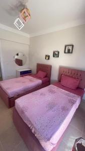 two beds in a room with pink sheets at فيلا دوبلكس في العين السخنة في قرية بلو باي أسيا عروس السخنة in Ain Sokhna