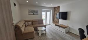 a living room with a couch and a television at Apartmani Lucija 2 in Zubovići