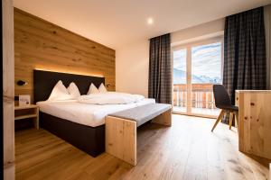a hotel room with a bed and a large window at Hotel Antholzerhof in Anterselva di Mezzo