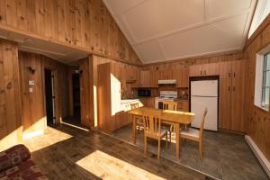 a kitchen with wooden walls and a wooden table and chairs at Chalet des Boisés 10 in Murdochville