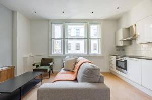 Una sala de estar con un sofá y una cocina. en Stylish Soho&Covent Garden Retreat, en Londres
