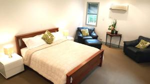 a bedroom with a large bed and a chair and a chair at Lush & Co Auckland Bed & Breakfast in Auckland