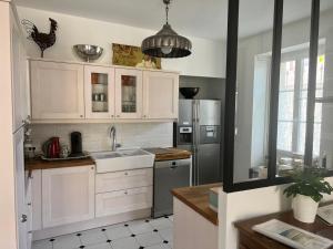 una cucina con mobili bianchi e un frigorifero in acciaio inossidabile di Le gîte de L'Echappée Champenoise a Sept-Saulx Altre 43 foto