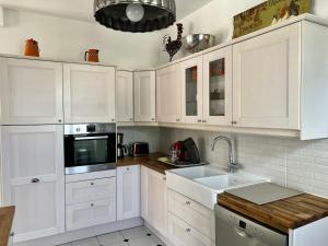 una cucina bianca con mobili bianchi e un lavello di Le gîte de L'Echappée Champenoise a Sept-Saulx