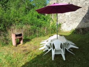 una mesa y una silla bajo una sombrilla en la hierba en Gîte Dornecy, en Dornecy