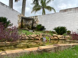 a pond in a garden with palm trees in the background at Pousada Recanto das Palmeiras in Areado