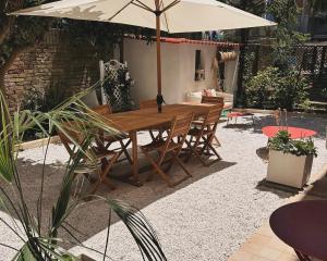 チヴィタノーヴァ・マルケにあるCasa Jouy con giardino a due passi dal mareの木製テーブルと椅子(傘付)