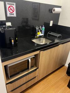 a kitchen counter with a sink and a microwave at Guaja 745 - Apartamento Luca in Belo Horizonte