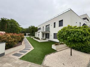 a large white house with a green yard at Penthouse Happy Seasons in Hajdúszoboszló