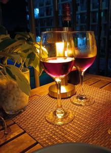 two glasses of wine on a table with a candle at Homey Apartment with Olympic-sized pools in Lapu Lapu City +44 photos