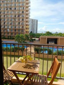 a table and chairs on a balcony with a building at Homey Apartment with Olympic-sized pools in Lapu Lapu City