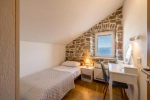 Un dormitorio con una cama y un escritorio y una ventana. en Seafront Villa Denis, en Bol