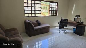 a living room with a couch and a desk and a chair at Suíte casal in Campo Grande