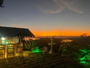a sunset with a table and chairs in a yard at Minas Em Marambaia in Rio de Janeiro