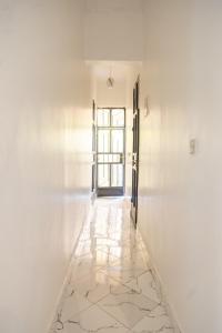 Un pasillo vacío con paredes blancas y una puerta. en Bienvenido a casa villa, en Arusha