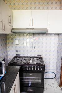 cocina con fogones negros y armarios blancos en Bienvenido a casa villa, en Arusha 13 fotos más