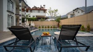a pool with two chairs and a table in front of a building at HONEY SUİTEs 1 in Fethiye +9 photos