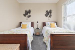 ジャクソンビル・ビーチにあるBe A Nomad - Beach Home Yard & Officeのベッドルーム1室(ベッド2台付)、壁に植物2本