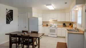 a kitchen with white cabinets and a table with chairs at Watermen's Cabana 2B - 2-Bed, 1-Bath - Walk To BEACH Access & PET Friendly! in Waves