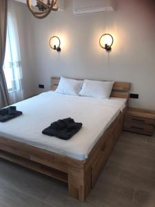 a bedroom with a large bed with two black clothes on it at Апартаменти ''Димови'' in Lozenets