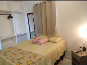 a bedroom with a bed with pink pillows on it at kitnet encantador no centro de Campina Grande- PB - apt 102 in Campina Grande