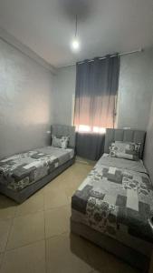 two beds sitting next to each other in a bedroom at Bel appartement moderne à Agadir in Dcheïra +3 photos