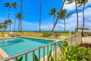 a balcony with a swimming pool and palm trees at Oceanfront Condo Stunning Sunrise and Ocean Views in Hauula