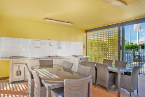 a dining room with a table and chairs and a kitchen at South Pacific Apartments in Port Macquarie