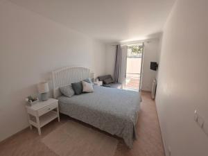 a white bedroom with a bed and a window at Alojamento da Praia da Areia Branca in Praia da Areia Branca +55 photos