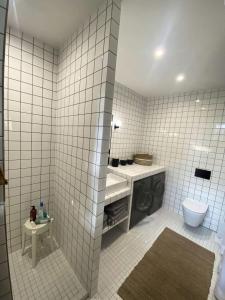 a white tiled bathroom with a sink and a toilet at Résidence 157-soulac Sur Mer - 157 - Maison de Charme de Style Basque avec Piscine Privée MAE-7391 in Soulac-sur-Mer