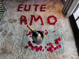 a bottle of wine and red flowers on a carpet at Minas Em Marambaia in Rio de Janeiro