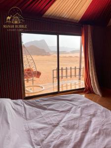 a bedroom with a bed and a view of the desert at Manar Bubbel Luxury Camp in Wadi Rum