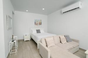 a white room with a bed and a couch at Apartamentos Ganesha Jacó in Jacó +123 photos