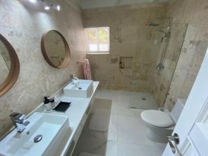 un bagno con lavandino, WC e specchio di Villa Allegria Los Lagos 57 a La Romana Altre 16 foto