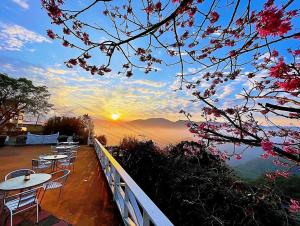 a view of the sunset from a balcony with tables and chairs at Alishan Tea Garden B&B in Fenchihu