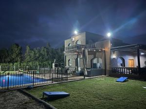 a house with a swimming pool at night at American Farm Villa Grand Casablanca/El Jadida in Zaouia Sidi Bou Azza