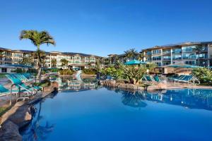 a pool at a resort with blue chairs and palm trees at Waipouli Beach Resort Exquisite Ocean Front Condo in Oceanfront H Building Sleeps 8 AC Pool in Kapaa +21 photos