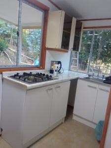 a kitchen with white cabinets and a stove at Hualqui Cabaña Santa Galoriza , Sector La Calle in El Cerrillo