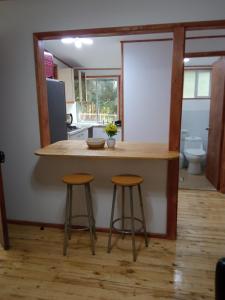 a kitchen with a counter and two stools at Hualqui Cabaña Santa Galoriza , Sector La Calle in El Cerrillo