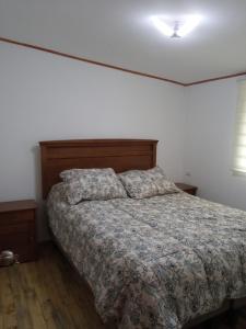 a bedroom with a bed with a comforter and two pillows at Hualqui Cabaña Santa Galoriza , Sector La Calle in El Cerrillo