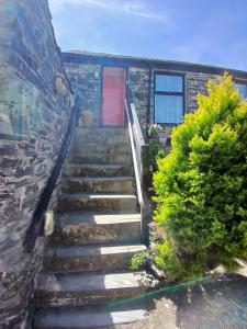 a stairway leading up to a house with a red door at The Chisel Coach House at The Bettle and Chisel in Delabole