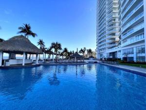 a large blue swimming pool next to a tall building at Apartamento pie de playa in Mazatlán