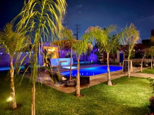 a pool at night with palm trees around it at Riad Safran Ralya in Marrakesh