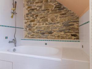a white bath tub in a bathroom with a stone wall at Charmant Gîte avec Jardin Clos au Cœur du Parc de Brière, Proche La Baule et Guérande - FR-1-306-863 in La Chapelle-des-Marais