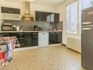 a kitchen with black cabinets and a white refrigerator at Gîte en campagne avec jardin privatif, près du Parc de Brière, tout confort, 3 chambres, Wi-Fi inclus - FR-1-306-893 in Missillac