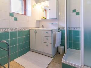 La salle de bains est pourvue d'une douche et de carrelage vert et blanc. dans l'établissement Charmante longère 3 chambres avec jardin clos, proche de Nantes, idéale pour familles et détente - FR-1-306-896, à Moisdon-la-Rivière 7 autres photos